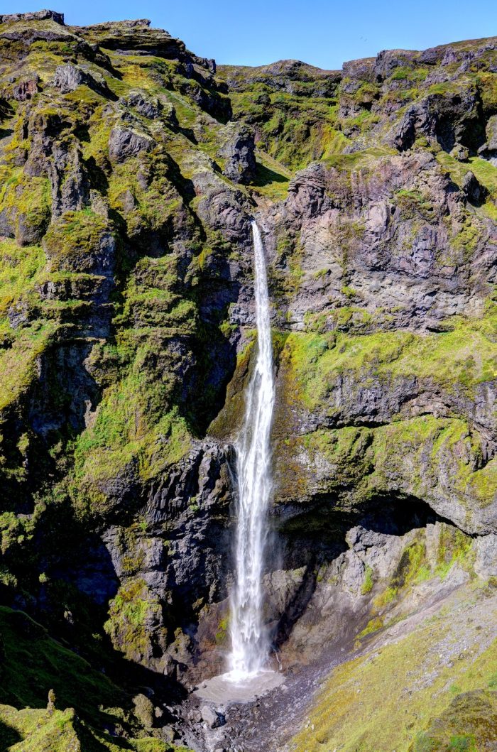 Cascata alta e sottile che cade da parete scura